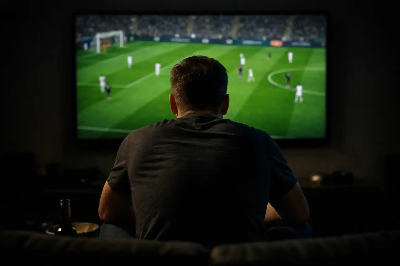 Person watching football match on large screen with focused attention